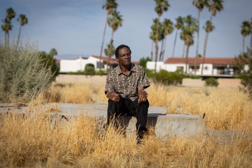 Palm Springs, CA - May 28: Alvin Taylor sits on a remaining foundation of a home in Section 14, as he and his wife Delia Ruiz visit an are in Palm Springs where their family's homes was seized on Tuesday, May 28, 2024 in Palm Springs, CA. (Jason Armond / Los Angeles Times)