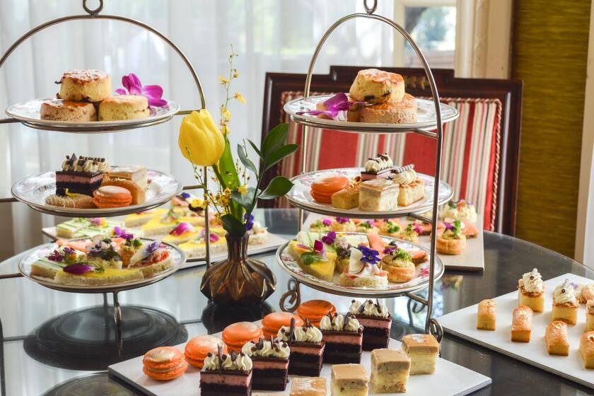 British tea spread with savory sandwiches, sweets and tea in floral china.