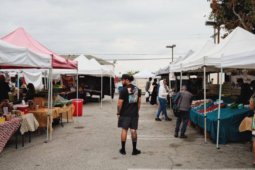 A shopper takes stock of the Crenshaw Farmers' Market on Saturday, Nov. 2, 2024.