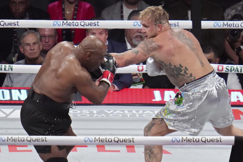 Jake Paul punches Mike Tyson in the face during their heavyweight boxing match