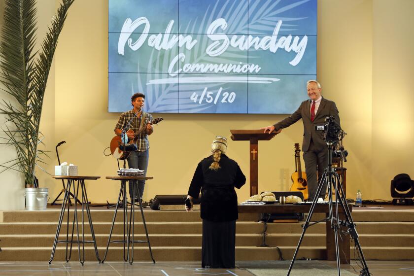 NEWBURY PARK, CALIFORNIA-APRIL 5, 2020-At the Godspeak Calvary Chapel in Newbury Park, California, communion was given inside the church on Palm Sunday using social distancing and other precautions due to coronavirus Covid 19. Pastor Rob McCoy, right, recently resigned from his post with the Thousand Oaks City Council because he was at odds with the city's social distancing orders. (Carolyn Cole/Los Angeles Times)