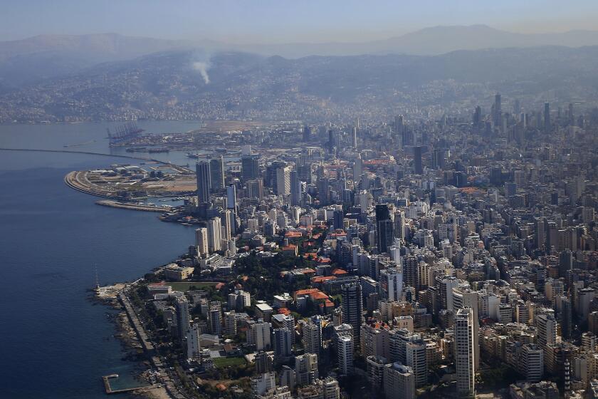 Smoke rises from a suburb, as a Greek military aircraft approaches with three tons of medicines, donated to Lebanese government, at the International Airport, in Beirut, Lebanon, Friday, Oct. 25, 2024. (Orestis Panagiotou/Pool photo via AP)