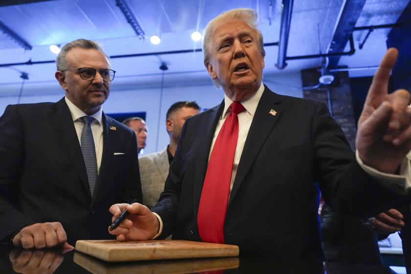 Republican presidential nominee former President Donald Trump signs autographs as Massad Boulos, listens as ee visits The Great Commoner, Friday, Nov. 1, 2024, in Dearborn, Mich. (AP Photo/Julia Demaree Nikhinson)