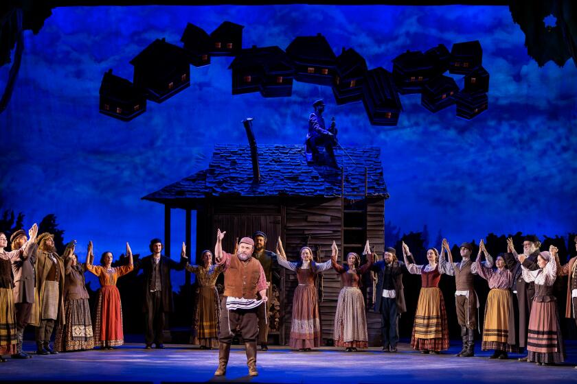 Jason Alexander (center) and a large group of actors onstage in Fiddler on the Roof