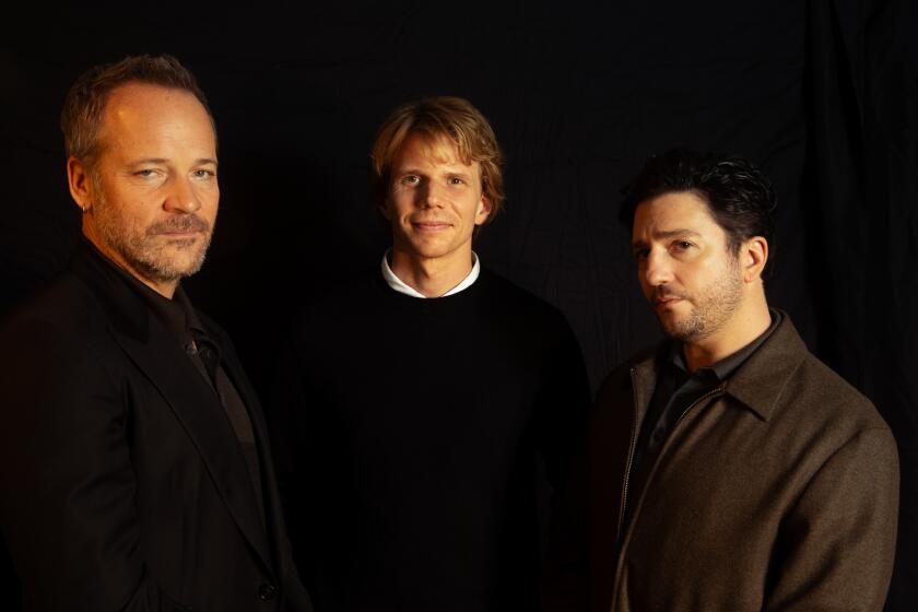 Three men in black pose for the camera.