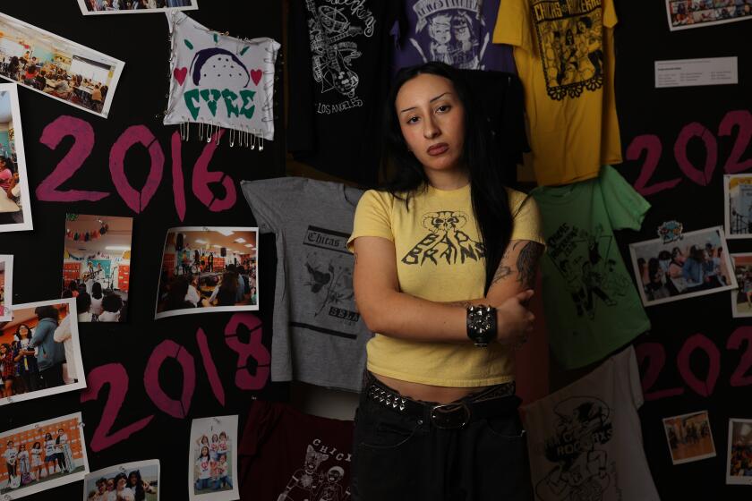 South Gate, CA - November 12: Priscilla Hernandez poses for a portrait with Chicxs Rockerxs memorabilia in the background at South Gate Museum on Tuesday, Nov. 12, 2024 in South Gate, CA. (Michael Blackshire / Los Angeles Times)