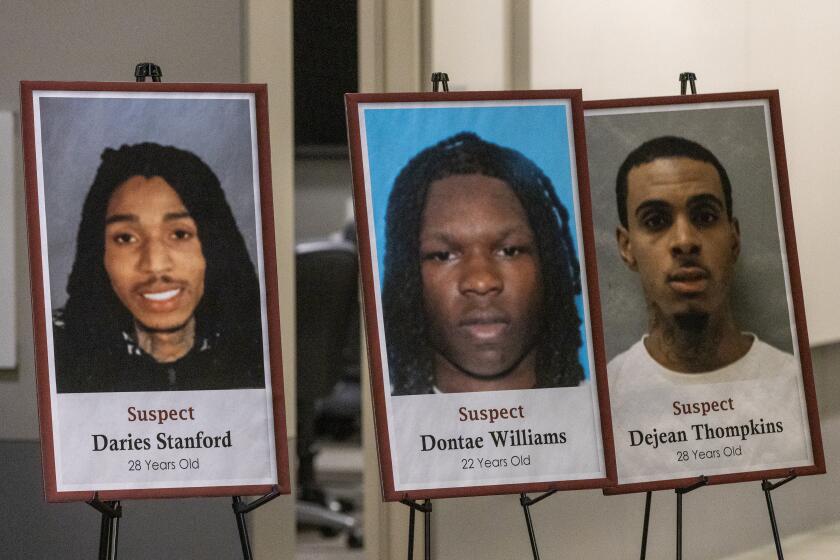 Los Angeles, CA - May 12: Photos of murder suspects Daries Stanford, left, Dontae Williams, center, and Dejean Thompkins are displayed as Capt. Jonathan Tippet, not pictured, who leads the Los Angeles Police Dept. Robbery-Homicide Division, speaks during a press conference to announce that Los Angeles police detectives took several suspects into custody in connection with a triple slaying outside a Benedict Canyon home earlier this year in LAPD in Los Angeles Friday, May 12, 2023. (Allen J. Schaben / Los Angeles Times)