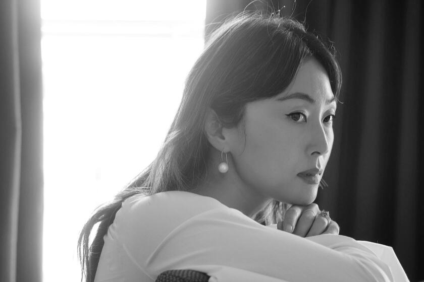 Black and white portrait of Juhea Kim seated backwards at desk