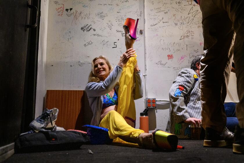 HOLLYWOOD, CA - SEPTEMBER 18, 2024: Mary Serritella, 71, stretches back stage before performing during the Comedy Pole Show at the Bourbon Room on September 18, 2024 in Hollywood, California. (Gina Ferazzi / Los Angeles Times)