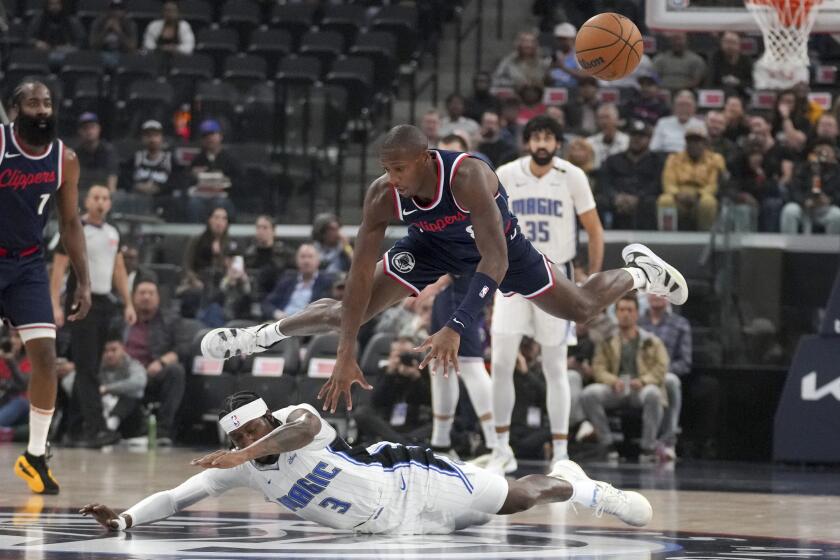 Los Angeles Clippers guard Kris Dunn (8) and Orlando Magic guard Kentavious Caldwell-Pope (3) battle for a loose ball during the first half of an NBA basketball game in Inglewood, Calif., Wednesday, Nov. 20, 2024. (AP Photo/Eric Thayer)