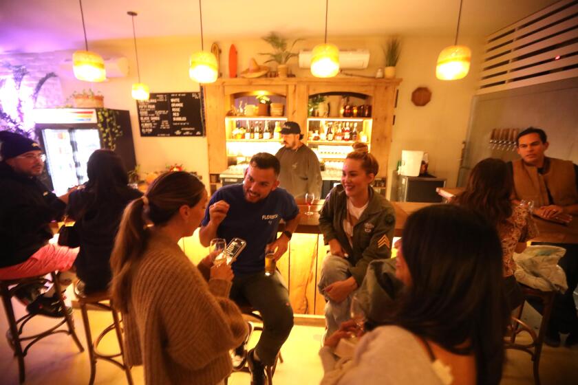 PALM SPRINGS, CA - NOVEMBER 7, 2024 - - Sesar Orozco, center, foreground) enjoys a conversation with friends at Las Palmas, a brewery and wine bar in Palms Springs on November 7, 2024. Rey Romero, right, is co-owner of Las Palmas. Sesar is a florist in Palm Springs who also grew up there. He and a bunch of his friends left their hometown after high school to live in bigger cities - San Diego, San Francisco - before deciding to come home and open businesses in Palm Springs, Indio and Coachella - reshaping their home town in their own image, younger and cooler. (Genaro Molina/Los Angeles Times)